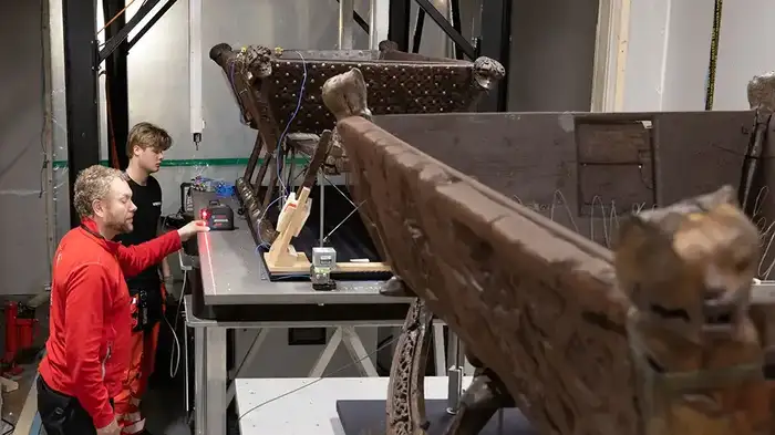 Two men are studying a wooden sledge from the Viking Age