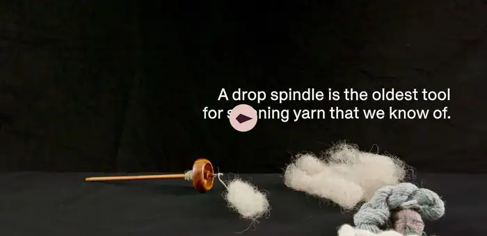 A spindle made of wood, wool, and twine placed on a table.