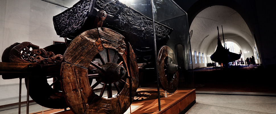 Bilde av en vogn fra vikingtiden som er stilt ut i en utstillingen
