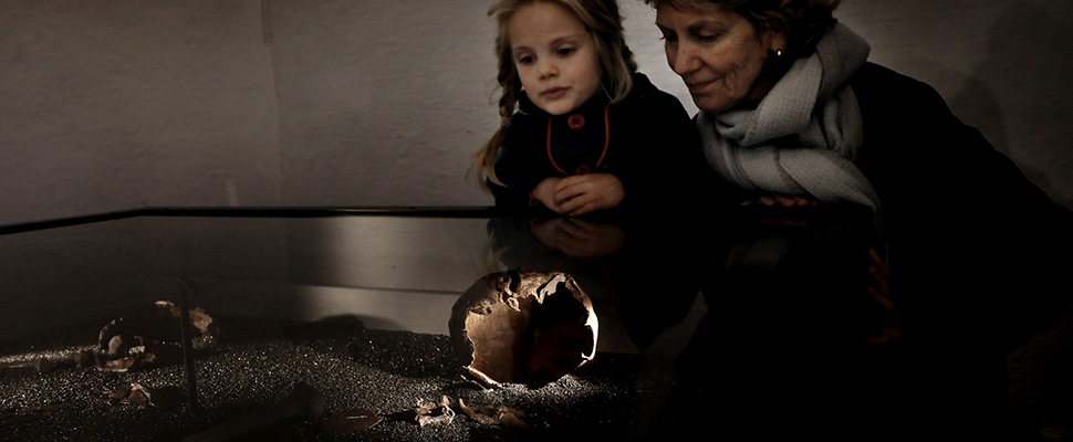 En jente og en dame ser på skjelettenne til de to kvinnene som ble funnet i vikingskipet Osebergskipet.