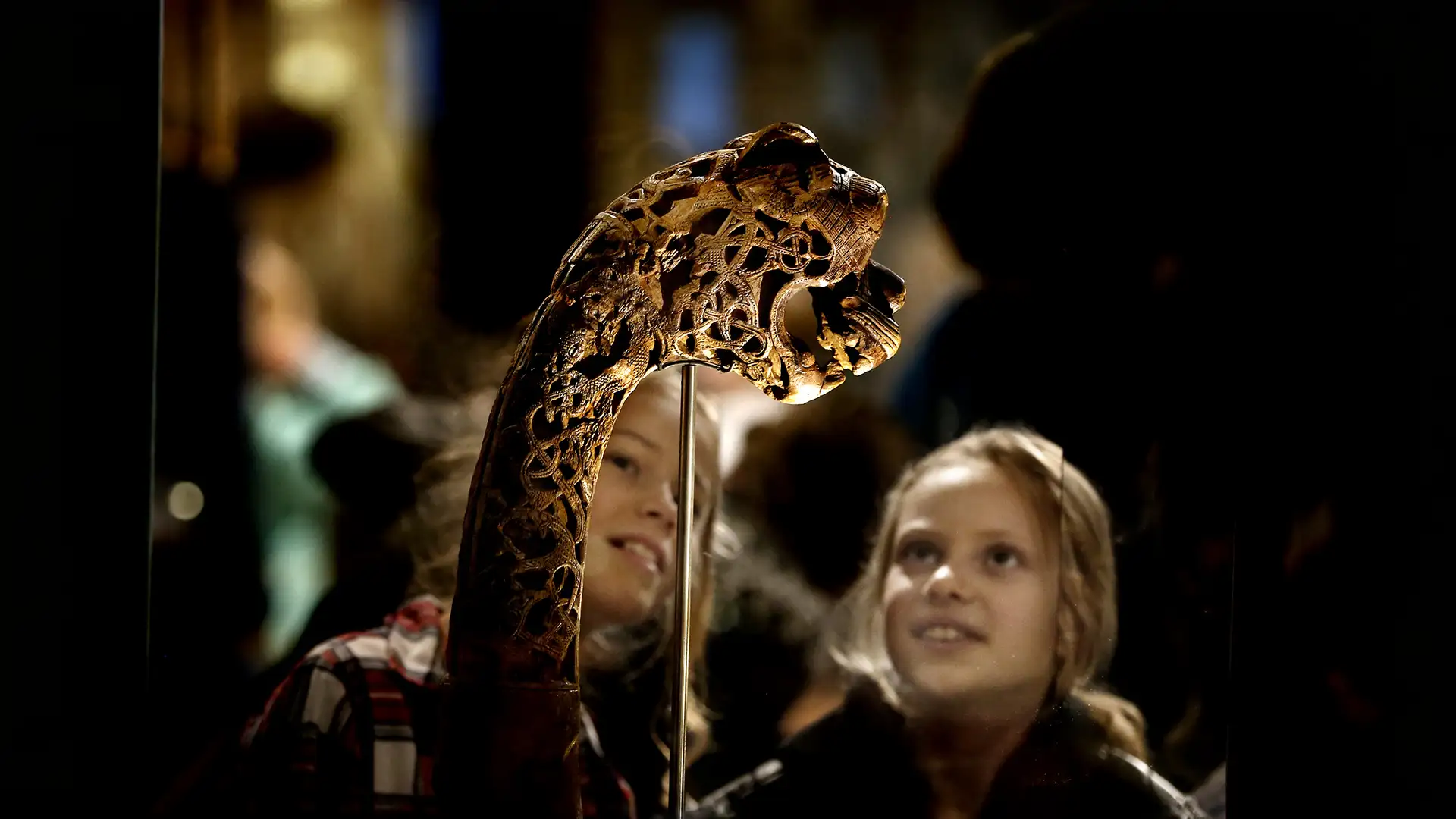 To jenter ser på en dyrehodestolpe utstilt i et museum.