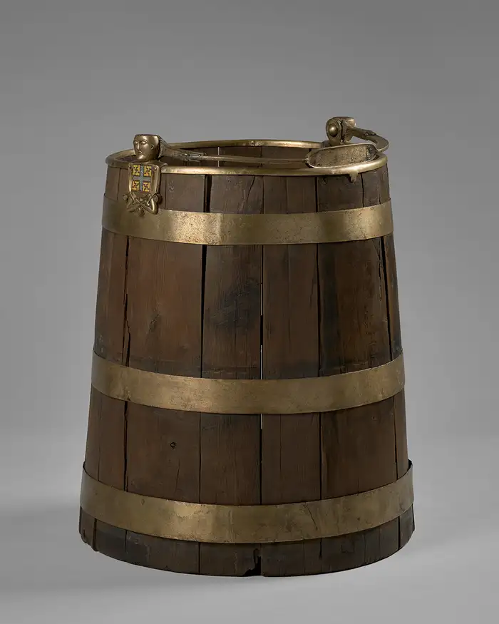 A bucket with two figures sitting on either side where the handle is attached.