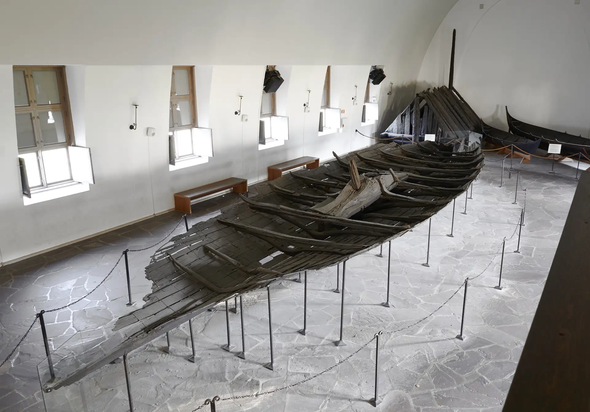 Deler av et vikingskip står utstilt i et rom.